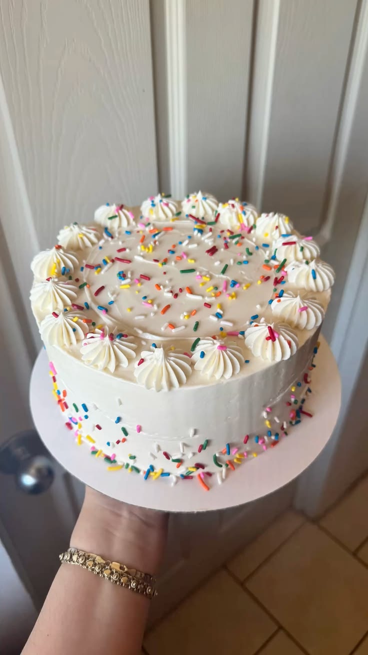Bolo branco decorado com confetes coloridos e rosetas de chantilly