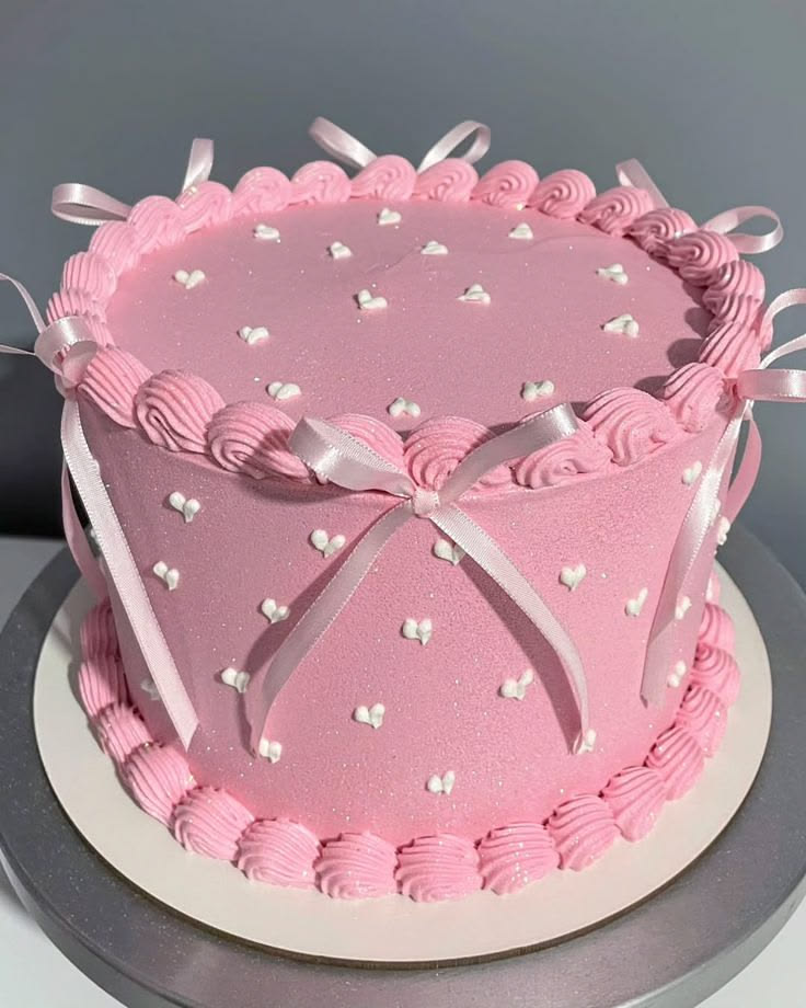 Bolo rosa decorado com laços cor-de-rosa e corações brancos